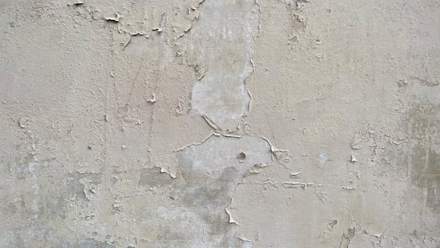 A close-up of a textured plaster wall with peeling paint, ideal for backgrounds.