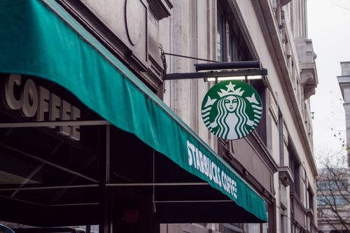 Free Exterior view of a Starbucks coffee shop in a city setting, featuring signage and awning. Stock Photo