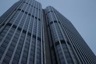 从低角度仰望未来主义摩天大楼，光滑的玻璃立面映衬着晴朗的天空