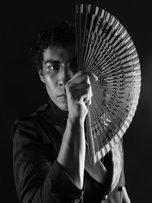 Free Elegant male dancer posing with a decorative fan in dramatic black and white. Stock Photo