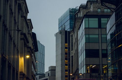 Free Modern city buildings with glass facades reflecting evening light, creating a dynamic urban landscape. Stock Photo