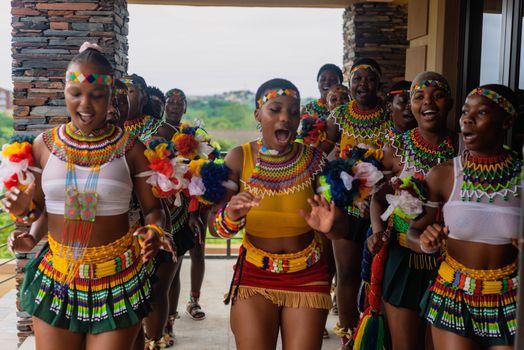 A group of Zulu women in traditional attire dancing passionately outdoors, showcasing vibrant cultural heritage.