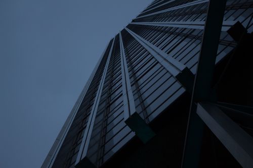 Free Low angle view of a modern skyscraper with glass facade at twilight. Stock Photo