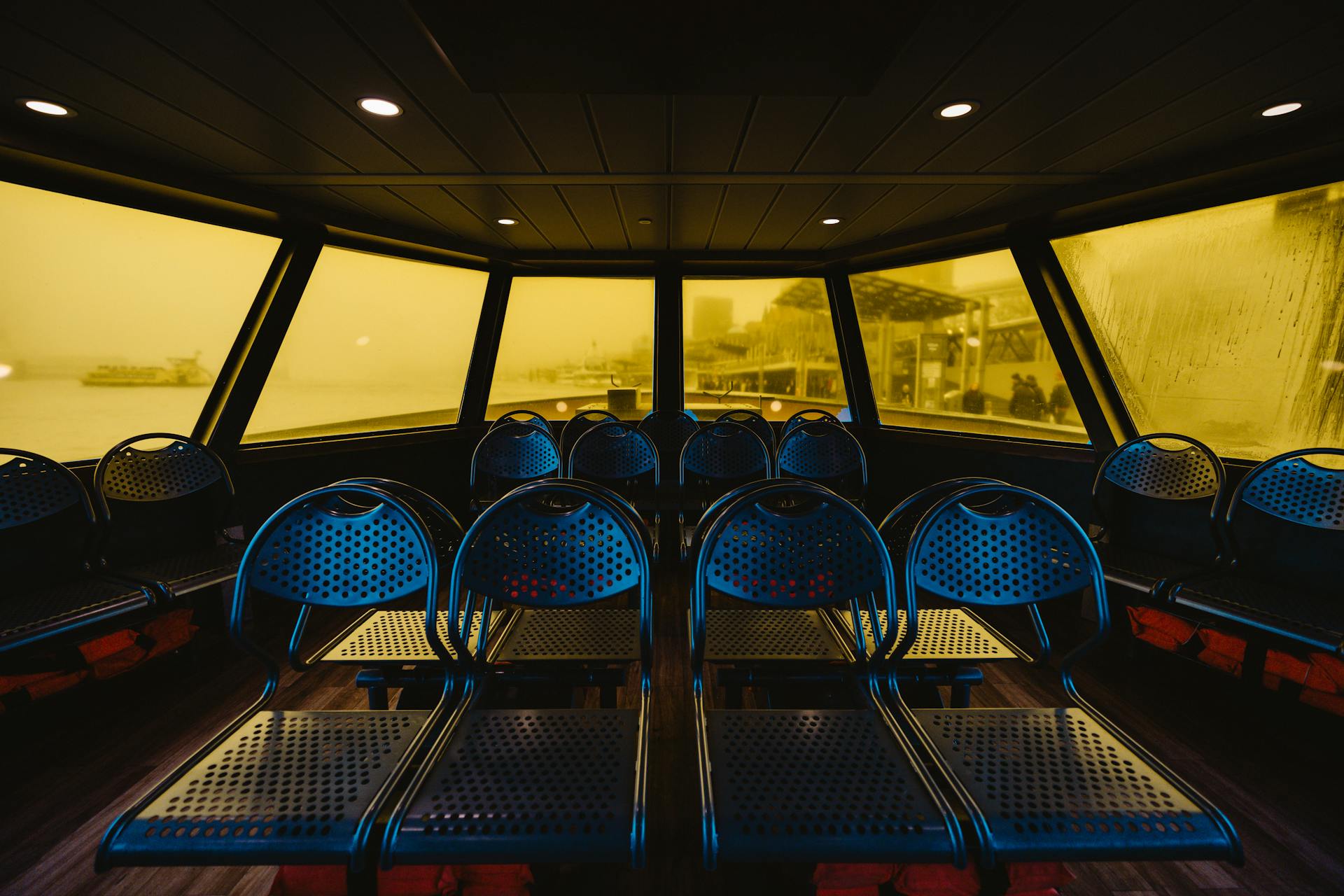 Interior view of empty ferry with modern seating and yellow-tinted windows in Hamburg, Germany.