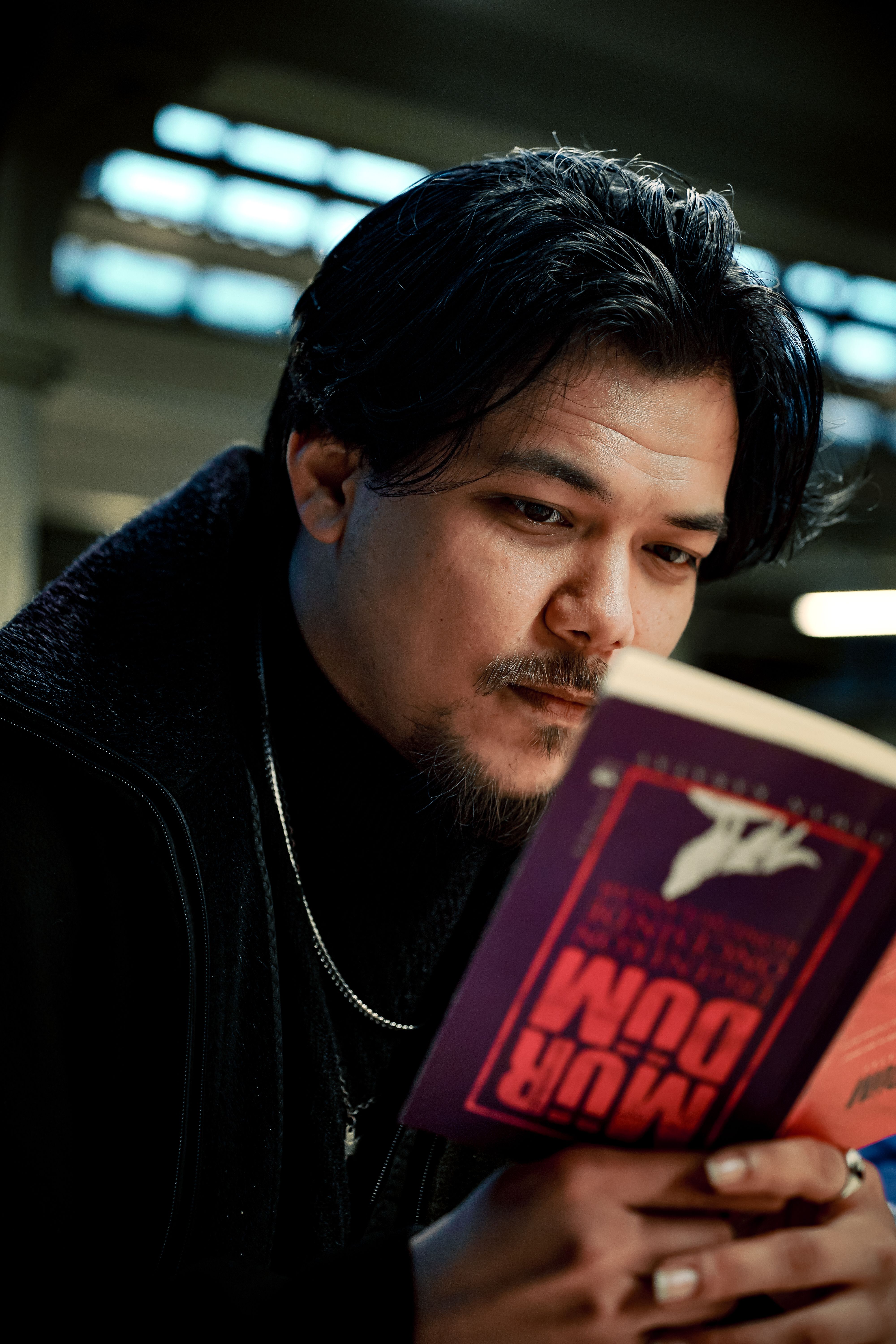 Focused man reading a book indoors, conveying concentration and interest.