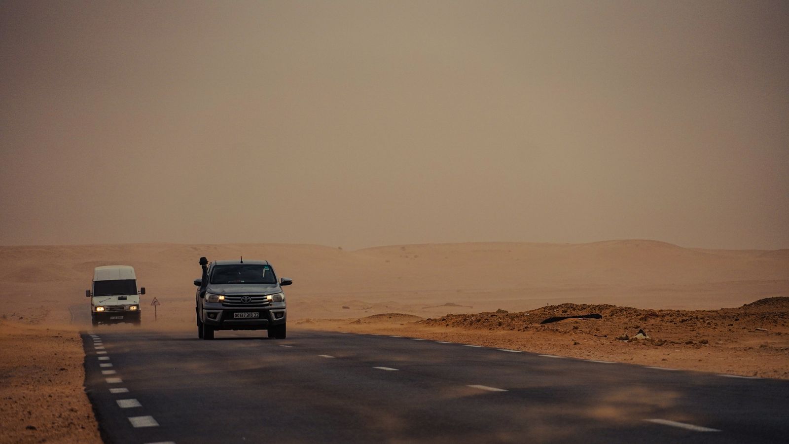 Vehicle driving down a hot summer desert highway with shimmering heat haze rising off the pavement