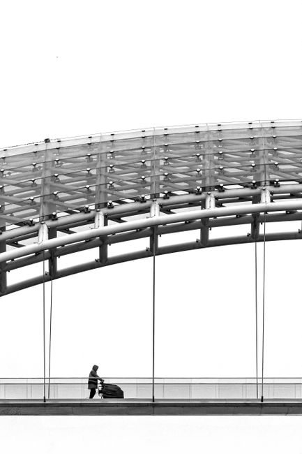 Black and white image of a person with stroller on Peace Bridge, Tbilisi.