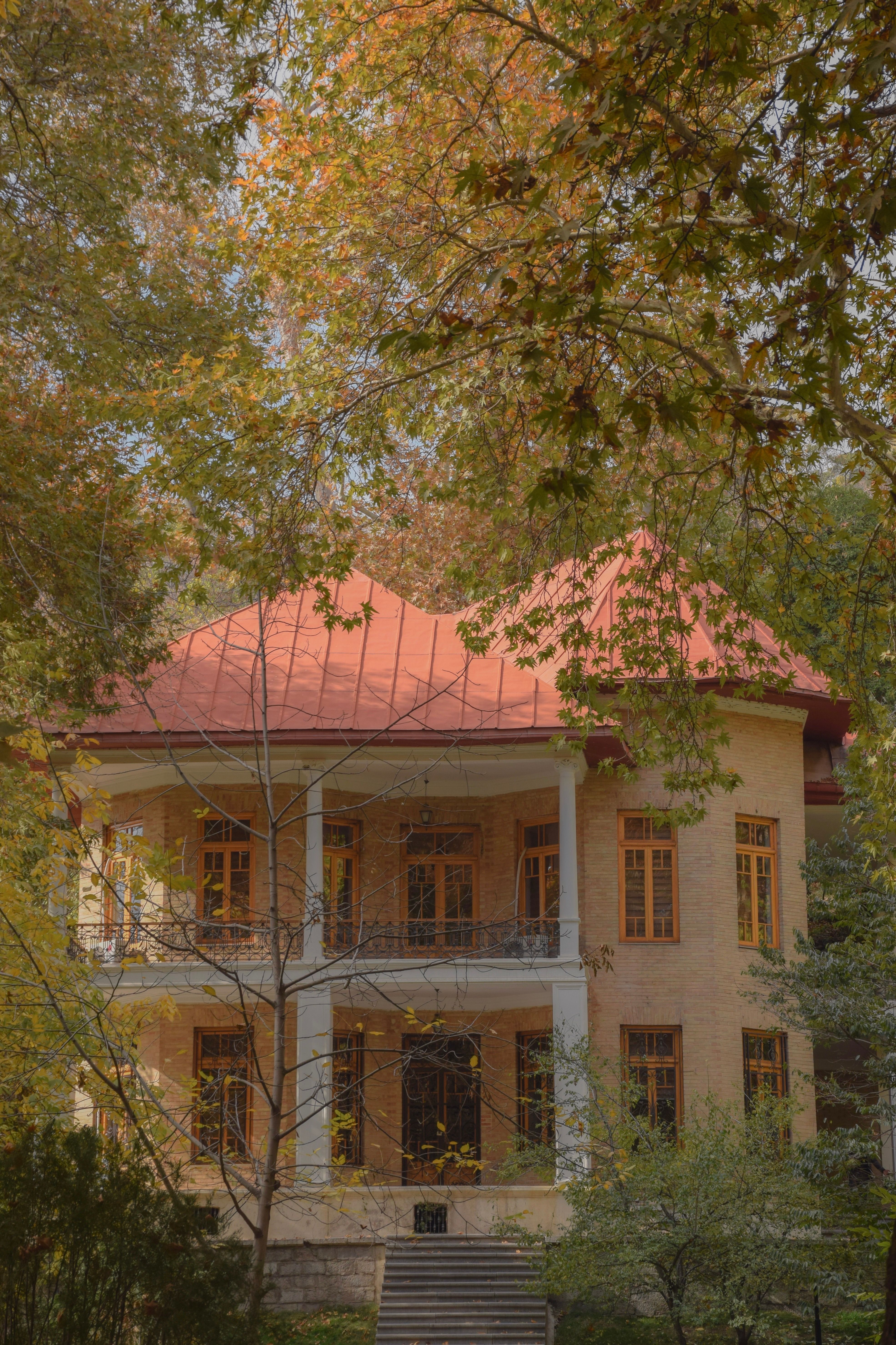 Quaint two-story house surrounded by vibrant autumn leaves, exuding warmth and nostalgia.