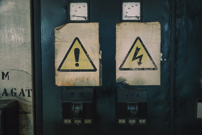 Close-up of industrial warning signs on an aged electrical panel