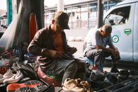 Portrait of a street shoe repairman working amidst footwear in Jakarta, Indonesia.