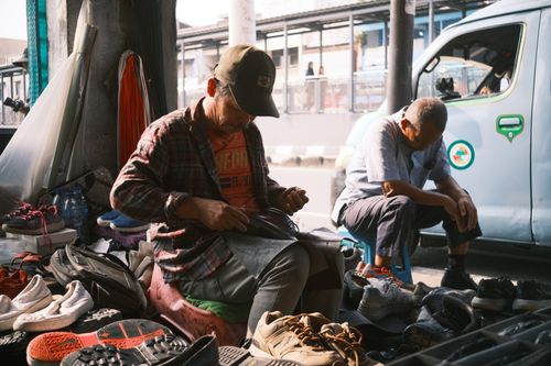 Free Portrait of a street shoe repairman working amidst footwear in Jakarta, Indonesia. Stock Photo