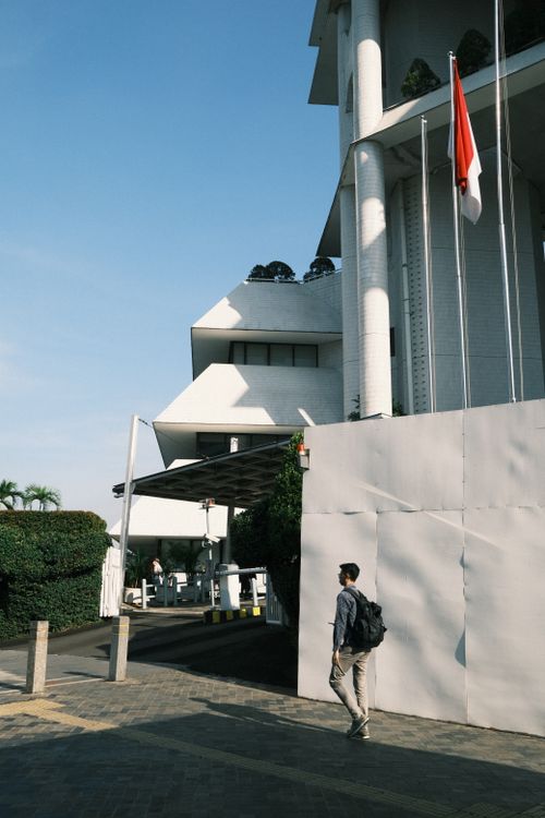Free A man walks by a modern building with the Indonesian flag in Jakarta, Indonesia. Stock Photo
