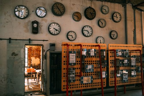 Free An array of vintage wall clocks in a dimly lit industrial setting, highlighting time and nostalgia. Stock Photo