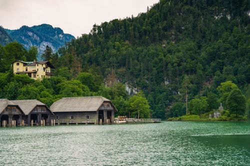 Free Picturesque boathouses at Königssee lake in Bavaria with lush alpine forest backdrop. Stock Photo