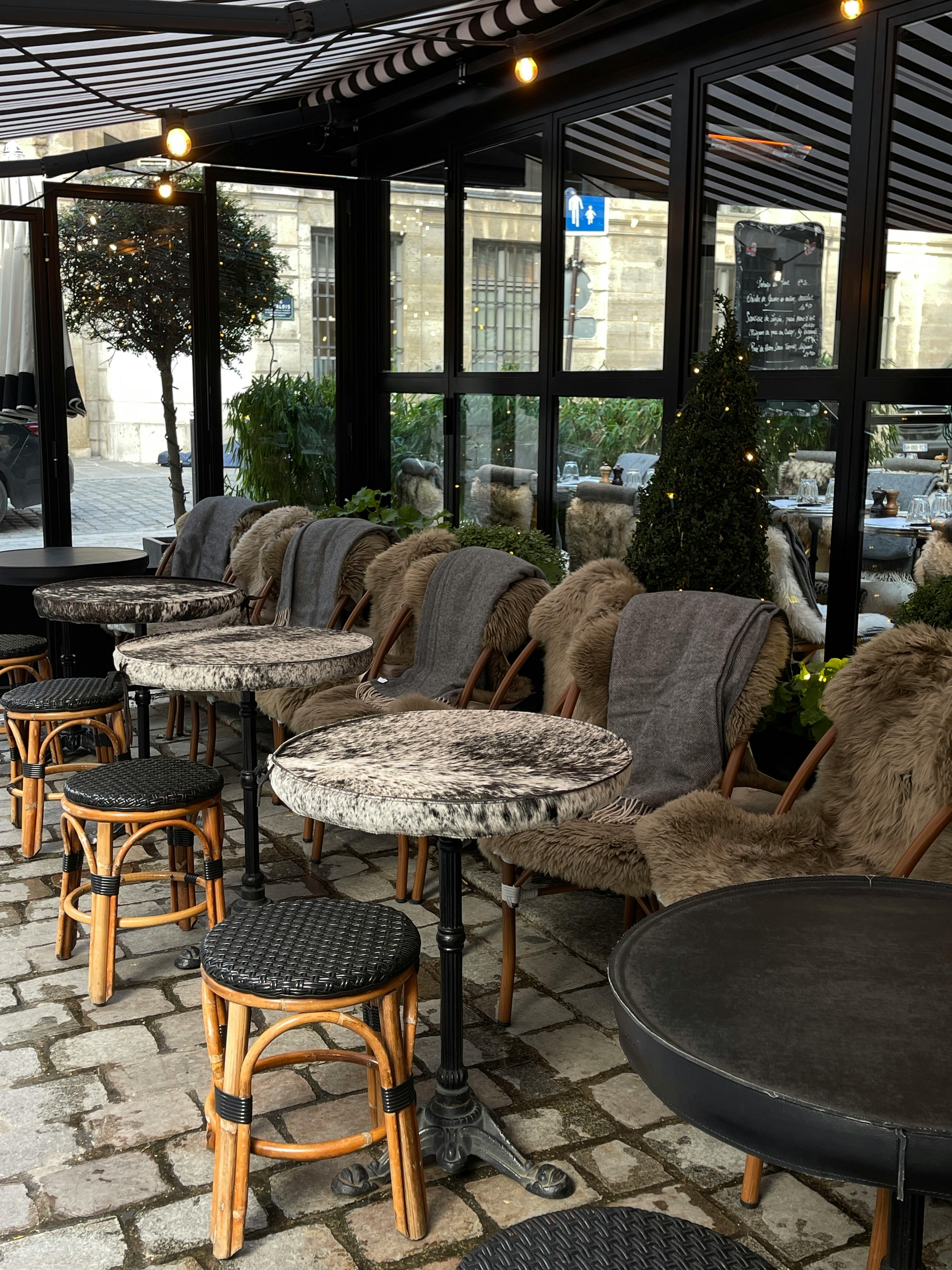 Outdoor cafe with fur-covered chairs, cobblestone street, and elegant atmosphere.