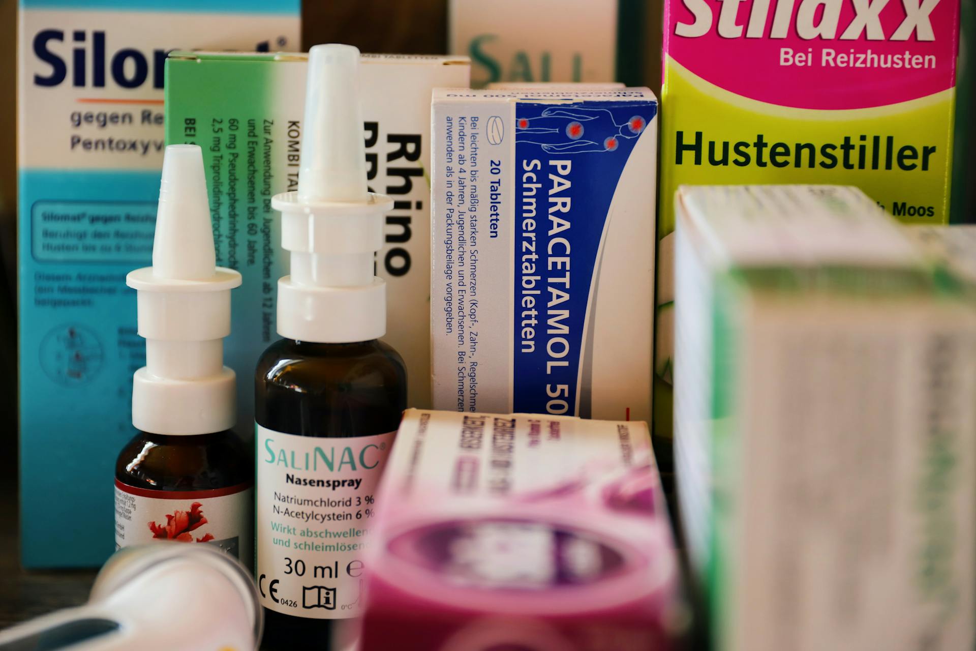 Assortment of cold and flu medications on a pharmacy counter.