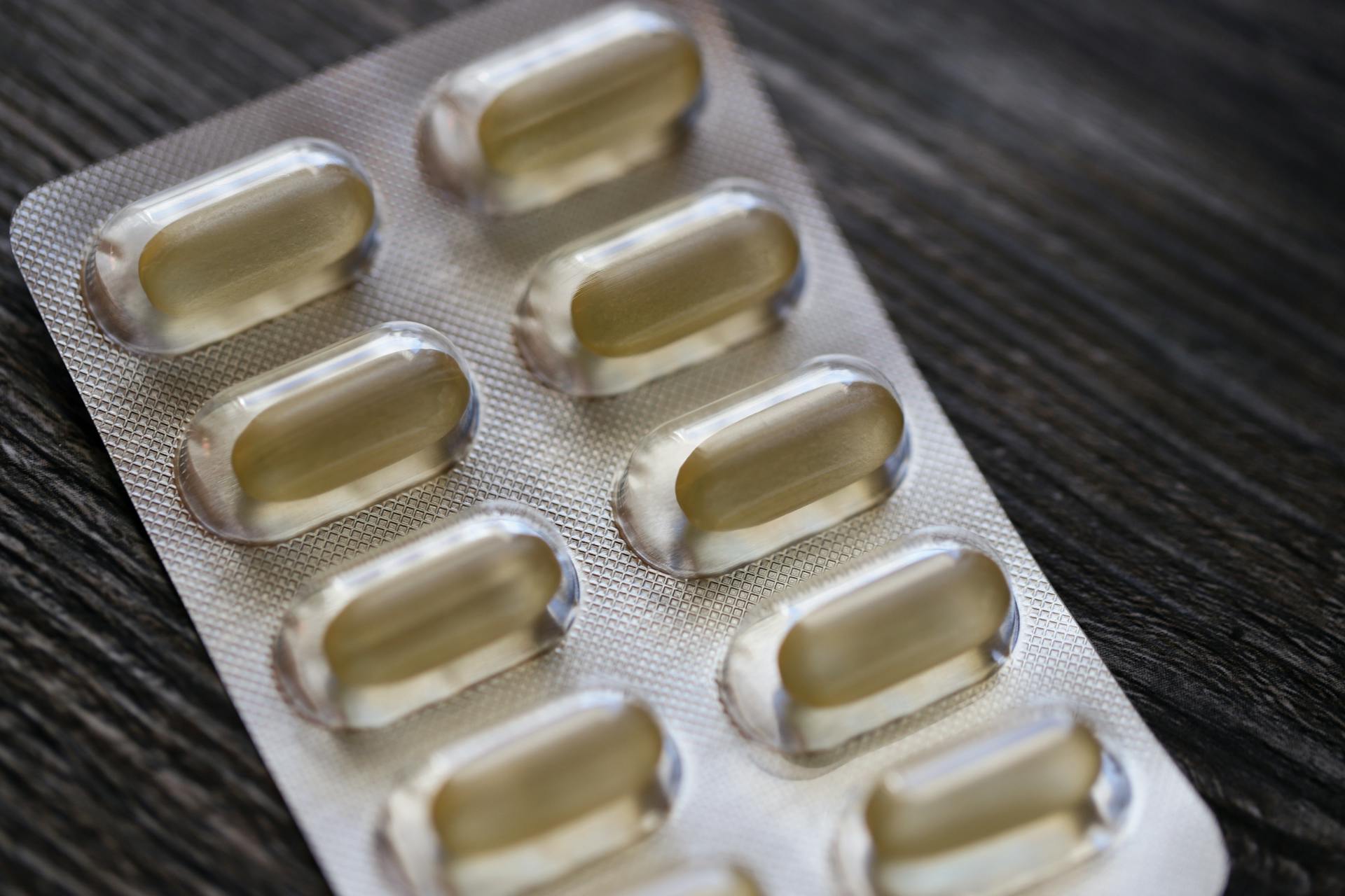 Detailed view of a blister pack with transparent capsules on a textured wooden background.