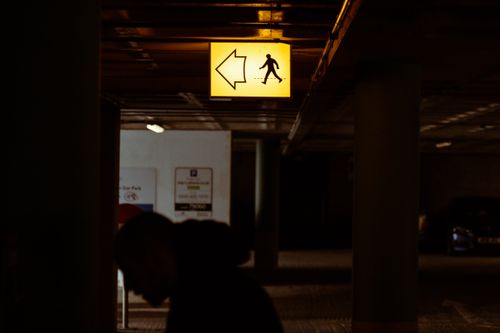 Free Dark parking garage scene with a glowing pedestrian arrow sign guiding the way. Stock Photo