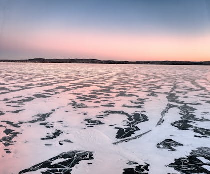 Beautiful frozen lake at sunrise, showcasing pink hues and icy textures at Camp Lacupolis, Minnesota.