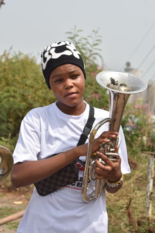 Free A young person plays a brass instrument outside on a sunny day wearing a black and white hat. Stock Photo