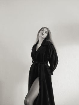 A stylish woman in a black coat poses against a neutral background.