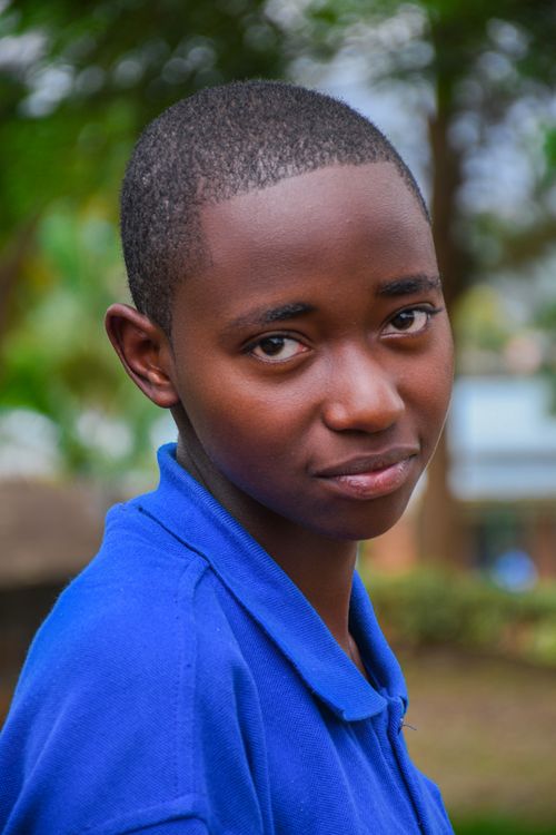 Free Natural portrait of a young person in a blue shirt with a serene expression outdoors. Stock Photo
