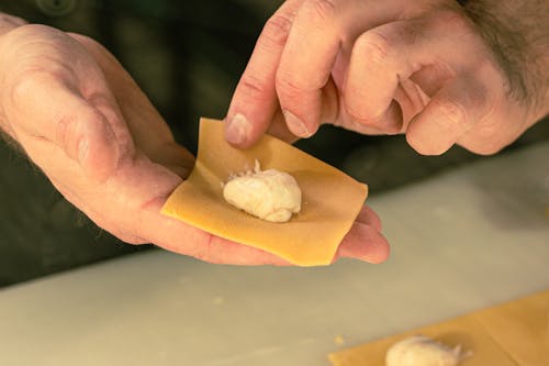 Free Hands crafting fresh ravioli with filling for homemade pasta dish. Stock Photo