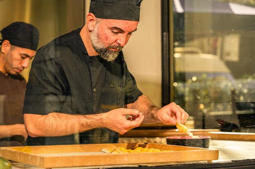 Free Chef in action making pasta in a professional kitchen, focusing intently on the details. Stock Photo