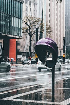 城市街道在雨中充满活力，设有紫色电话亭和现代建筑
