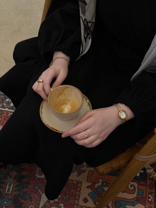 Free A woman holding a cup of coffee, showcasing jewelry in a cozy indoor setting. Stock Photo