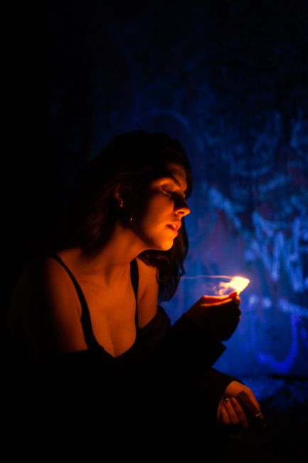 A mysterious portrait of a woman with a lighter casting a warm glow in the dark.