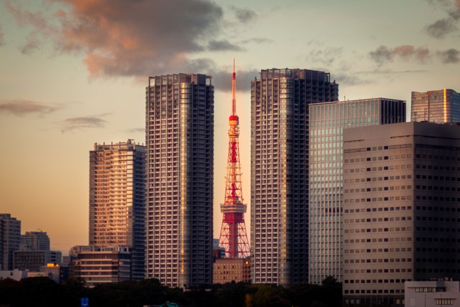 Tokyo Tower nestled between skyscrapers during sunset, capturing a serene urban landscape.