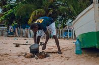 An angler tending a fire on a sandy beach in Luanda, Angola.