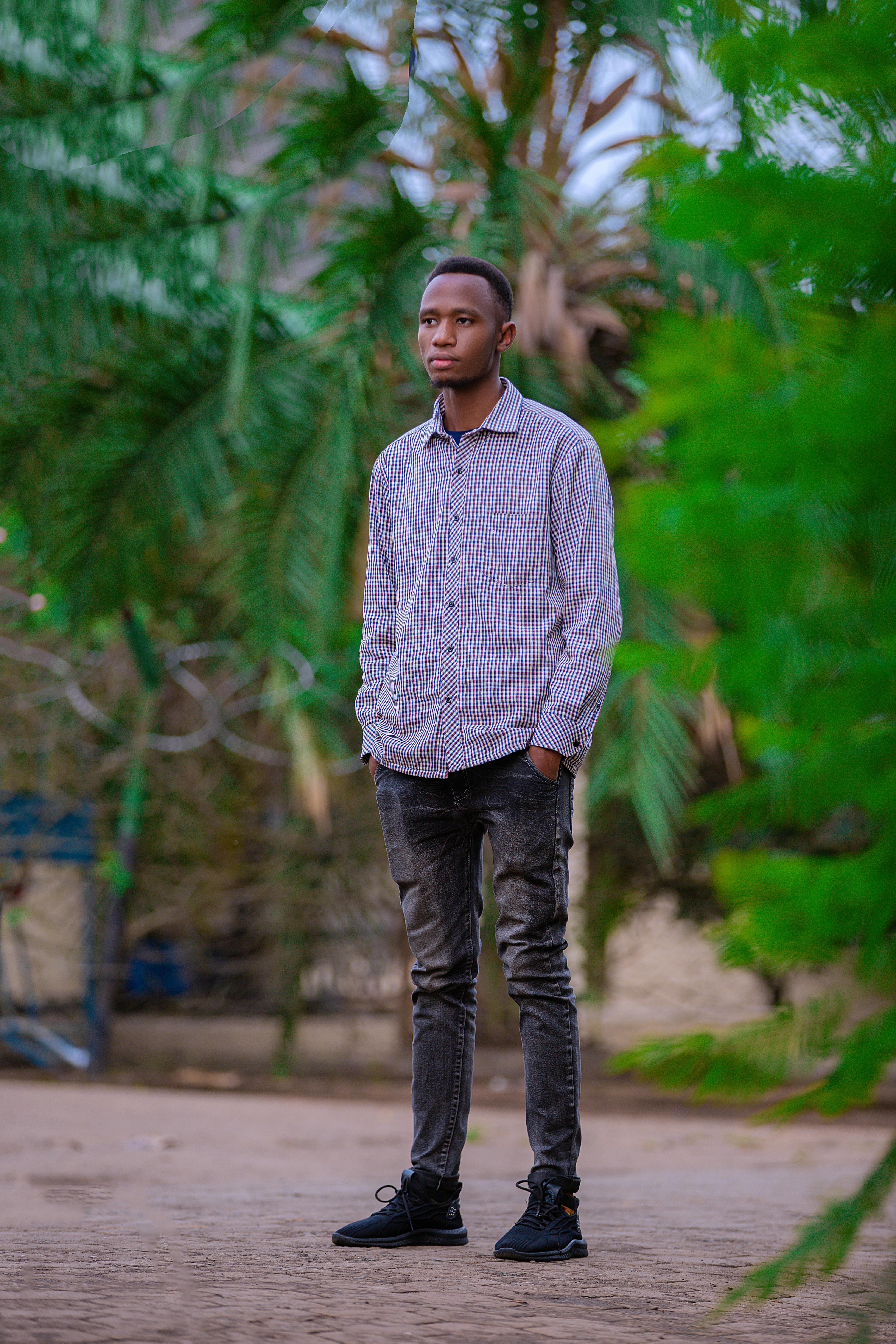 Gratis Un joven se encuentra al aire libre con ropa informal y rodeado de exuberante vegetación. Foto de stock