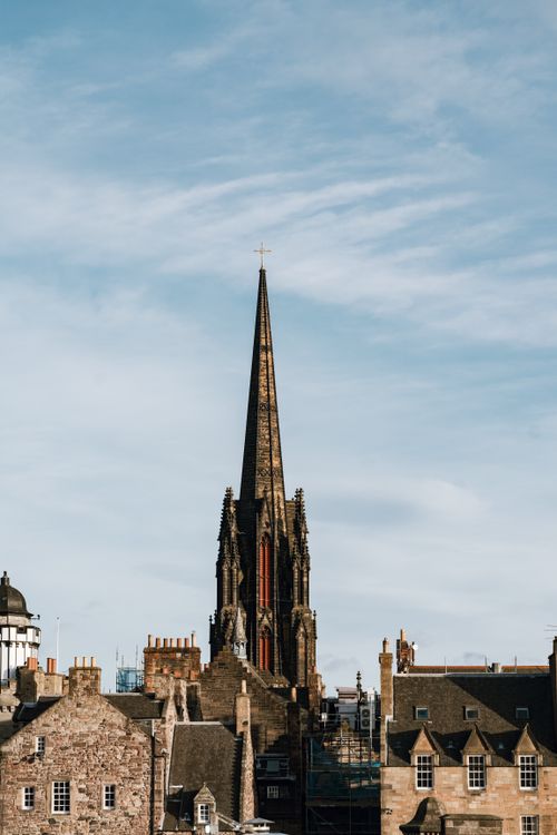 Free Stunning Edinburgh skyline featuring a Gothic-style building spire under a bright blue sky. Stock Photo