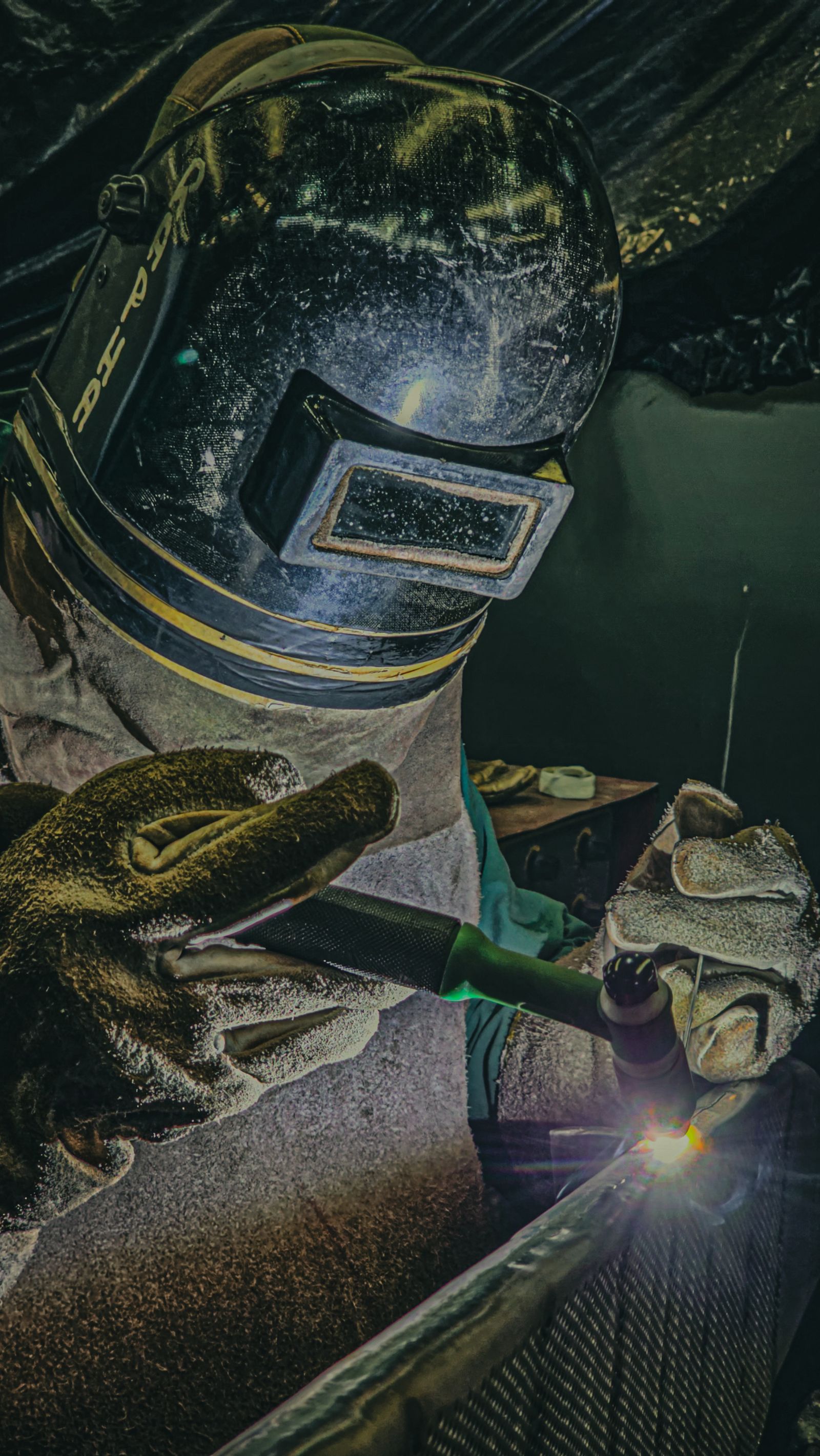 Welder performing TIG welding on a steel component while wearing protective equipment