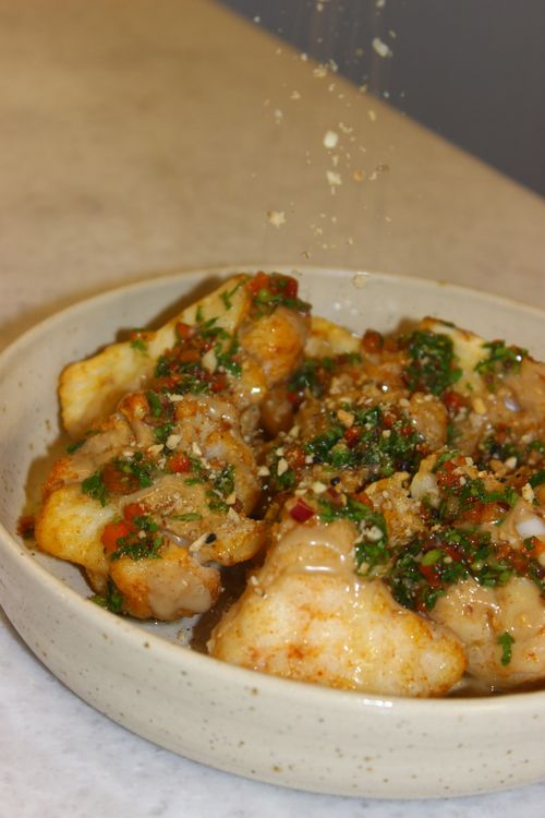 Free Mouthwatering spicy chicken garnished with herbs and spices on a stoneware plate. Stock Photo