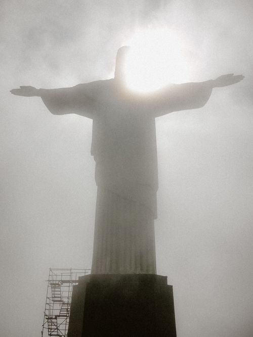 Free Silhouette of Christ the Redeemer statue enveloped in fog with sunlight shining through. Stock Photo