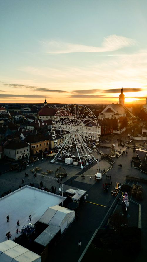 Free Stunning aerial shot capturing a Ferris wheel against a European town's sunset skyline. Stock Photo