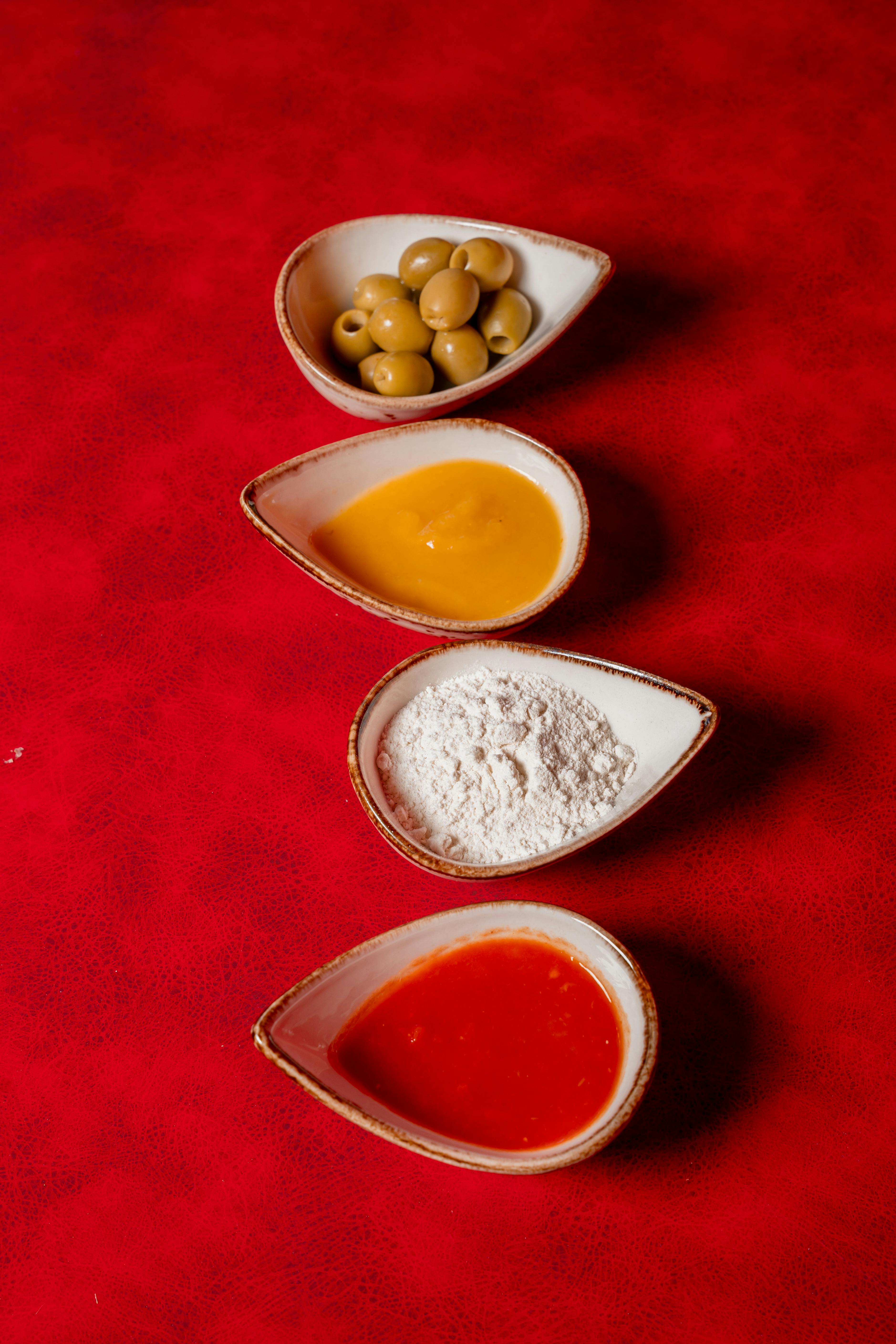Four key pizza ingredients beautifully arranged on a vibrant red backdrop.