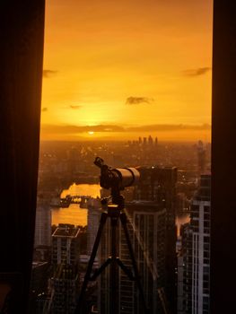 A breathtaking view of London's Canary Wharf skyline at sunset through a telescope.