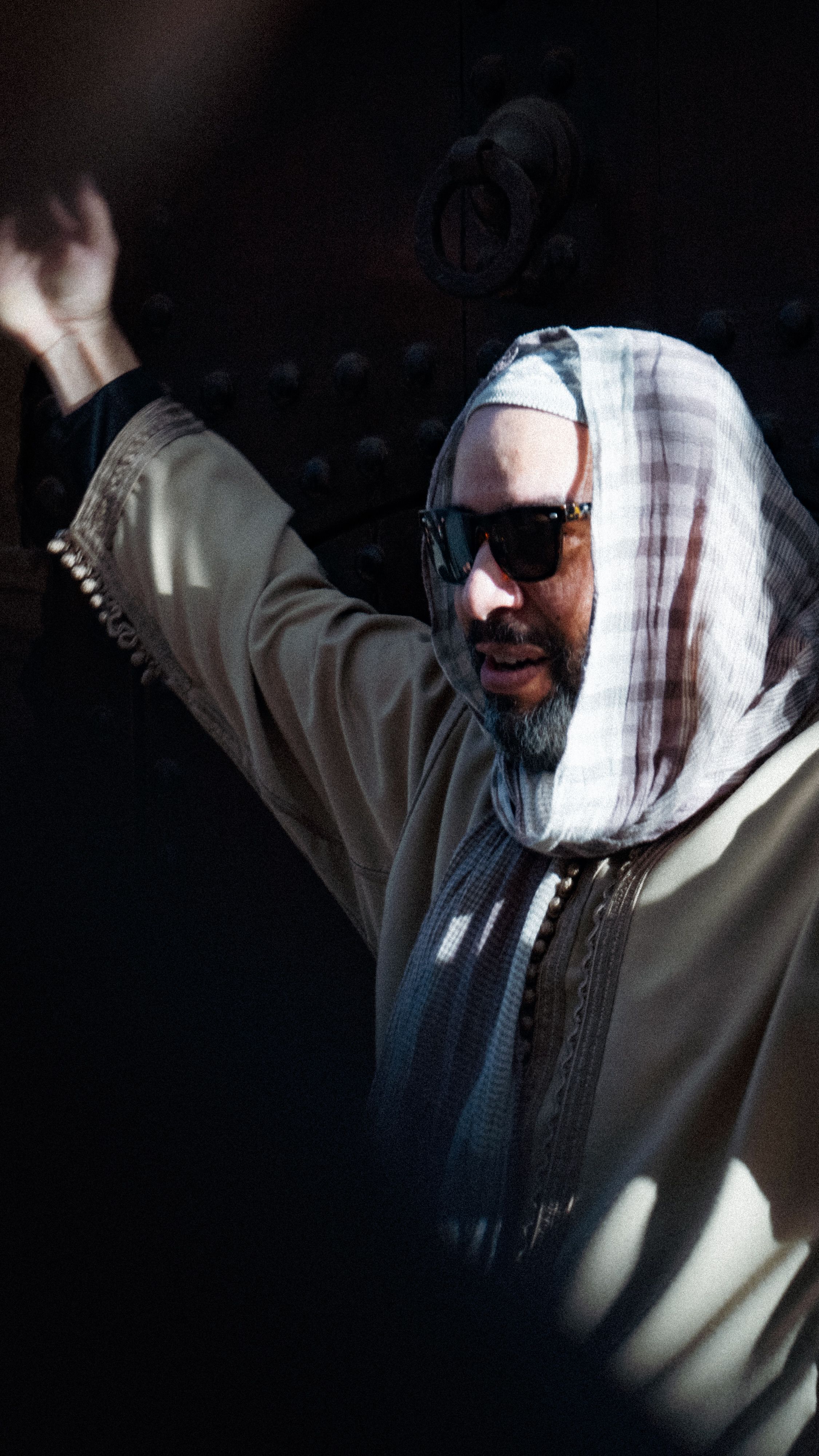 A man wearing sunglasses and a traditional Moroccan outfit stands outdoors in Rabat, Morocco.