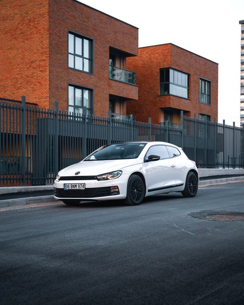 Free White Volkswagen Scirocco parked on city street against modern architecture in Ankara, Türkiye. Stock Photo