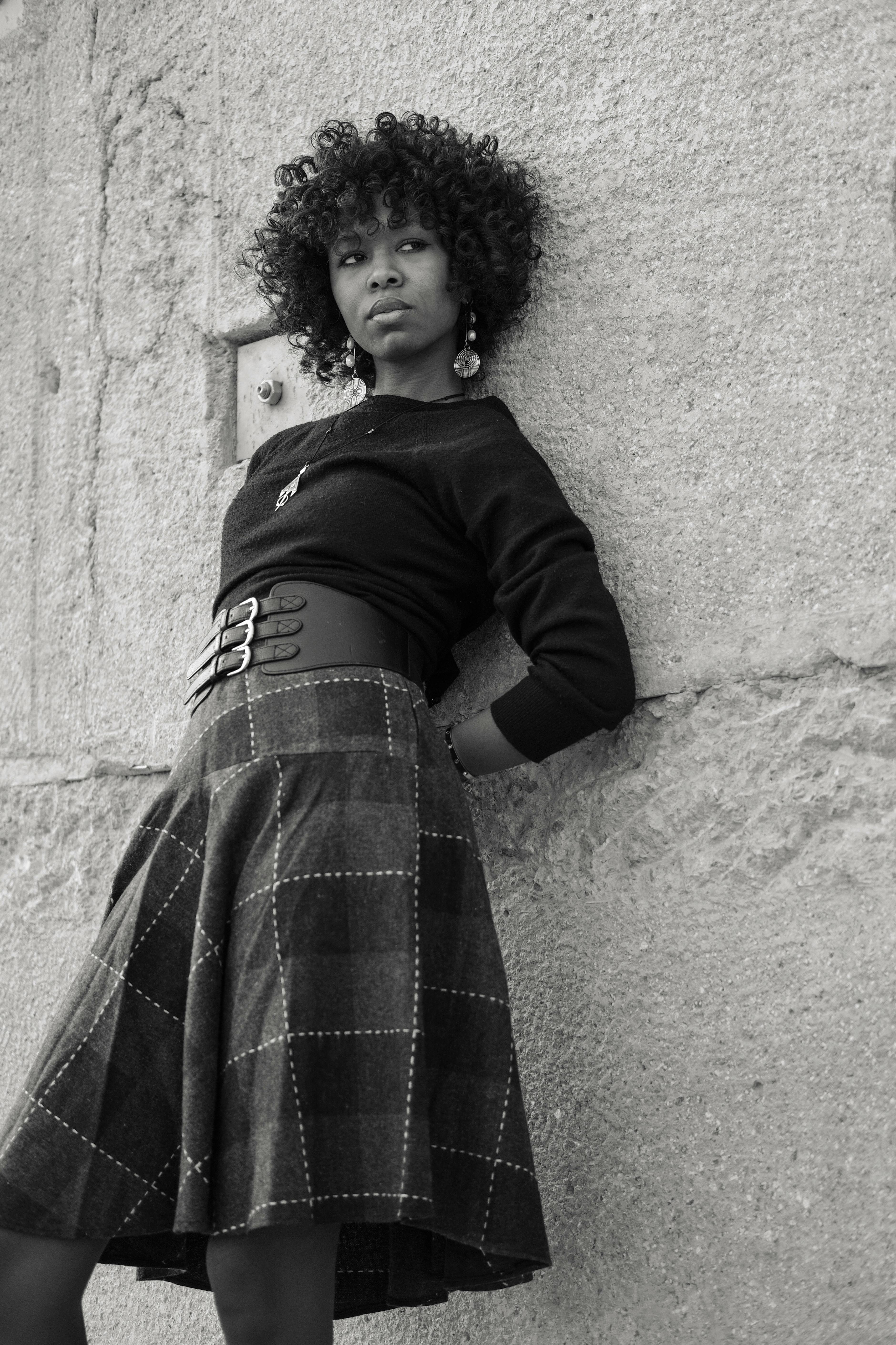Elegant portrait of a stylish woman leaning against a stone wall in Rabat, Morocco.