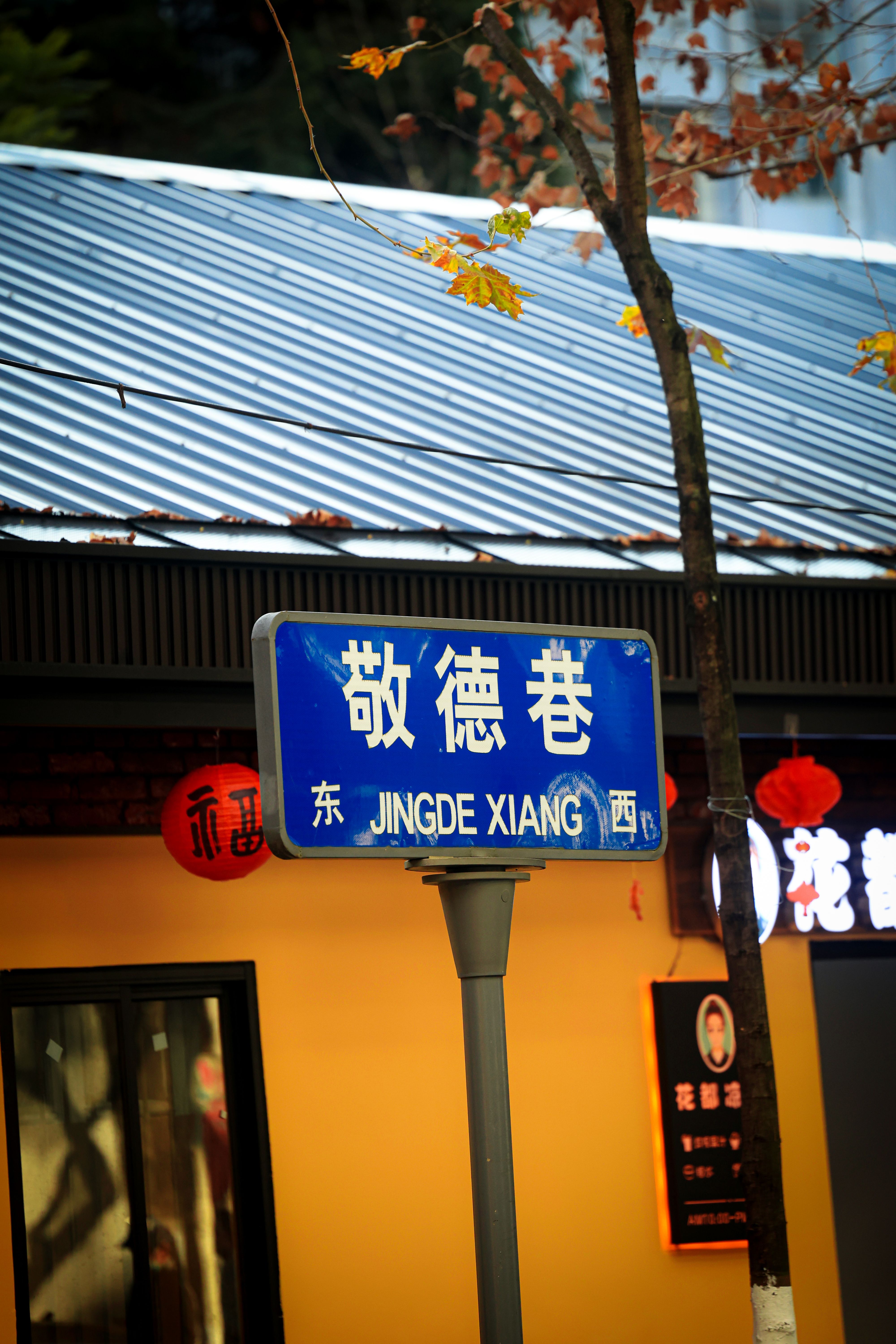 Street sign in Jingde Xiang, featuring autumn colors and traditional Chinese architecture in the background.
