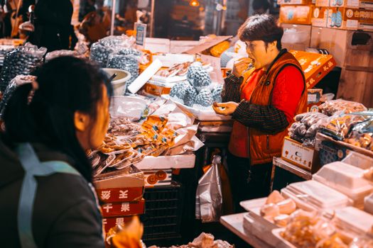 Colorful street market with vendors and various products displayed.