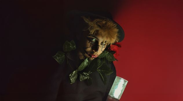 Dramatic portrait of a person with artistic makeup, leaves, and red background.