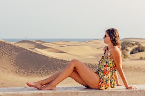 하늘에 대 한 해변에서 모래에 앉아 여자