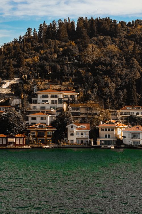 Free Picturesque coastal homes nestled by a lush, wooded hillside. Stock Photo