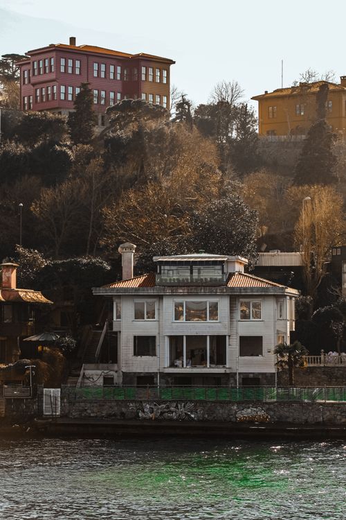 Free Charming waterfront house surrounded by lush trees in scenic landscape, ideal for travel inspiration. Stock Photo
